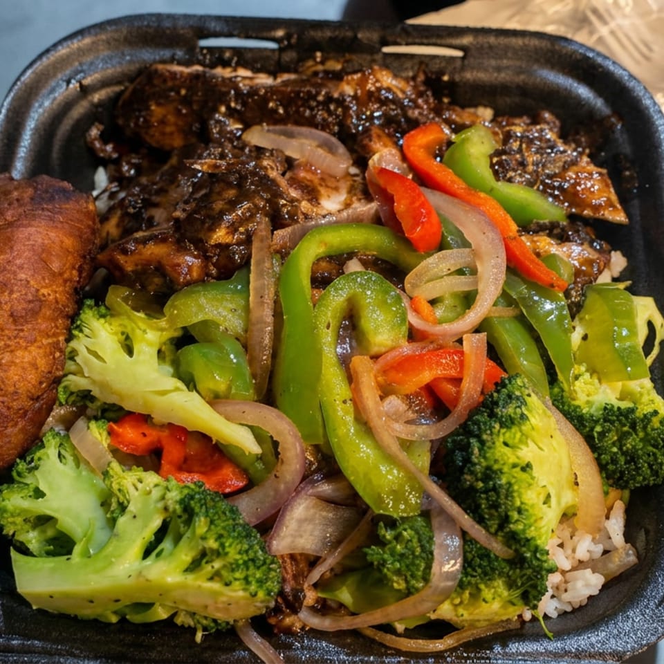 Takeout container filled with glazed meat, fried plantain, broccoli, peppers, onions, mushrooms, and rice.